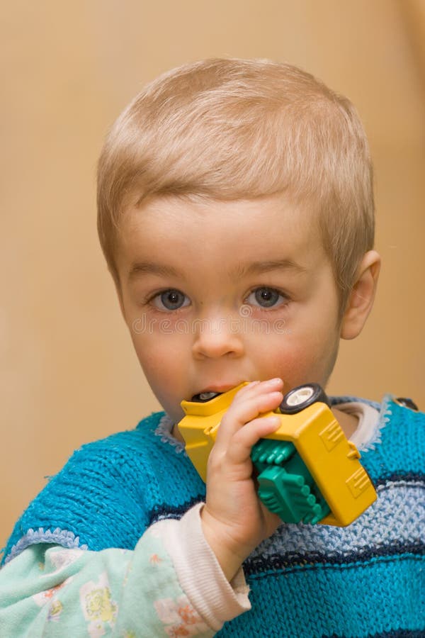 Cute small boy biting his plactic car toy