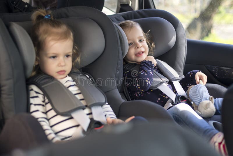 Cute small twins in car seats in the car