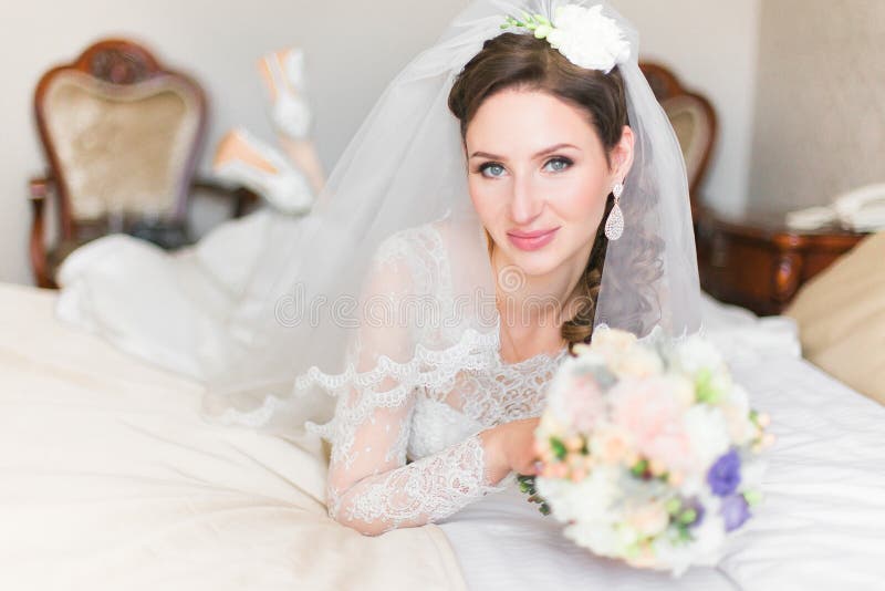 Cute smiling bride on the bed looking at camera