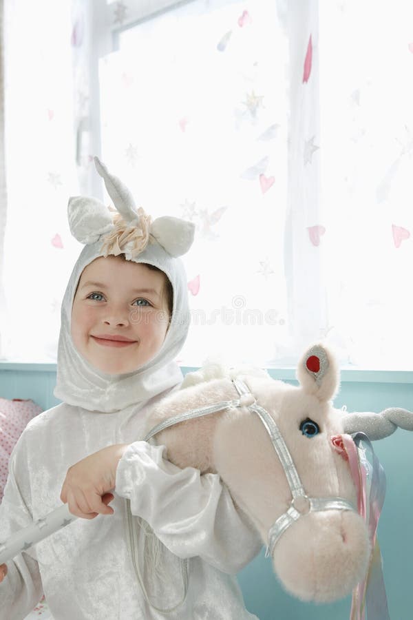 Cute Smiling Girl In Unicorn Costume With Toy Horse