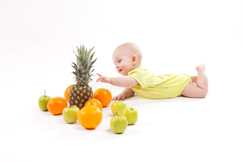 Cute smiling healthy child lies on a white background among frui