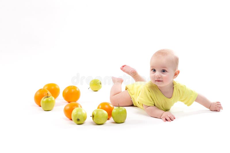 Cute smiling healthy child lies on a white background among frui