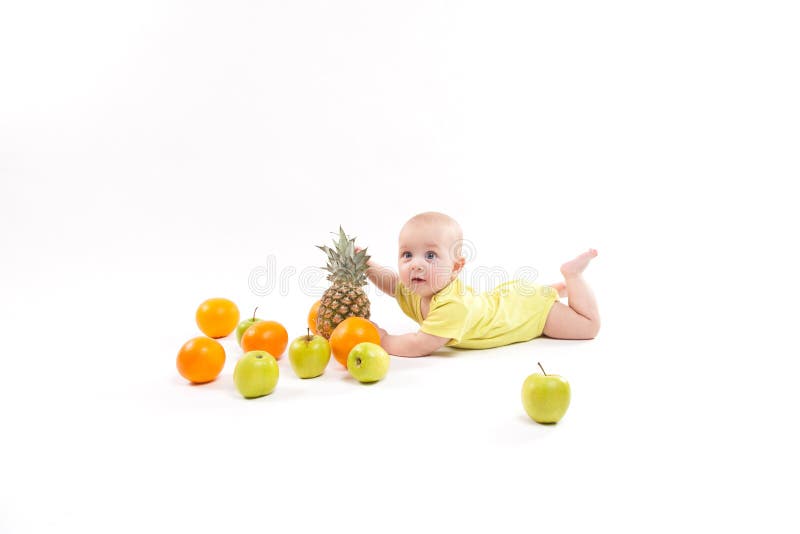 Cute smiling healthy child lies on a white background among frui