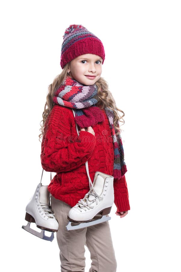 Cute smiling little girl with curly hairstyle wearing knitted sweater, scarf, hat and gloves with skates isolated on white.