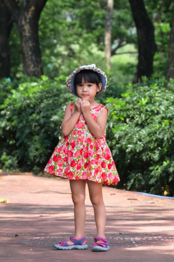 A Cute Smiling Little Girl in a Red Floral Dress is Walking and Having ...