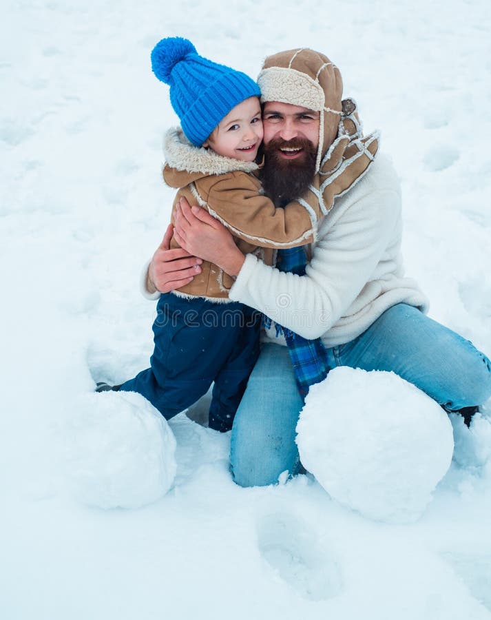 Cute son kramar sin pappa på vintersemester Pappa och pojken ler och kramar Glad leende familj på den soliga vinterdagen Julsemester Julfirandedag