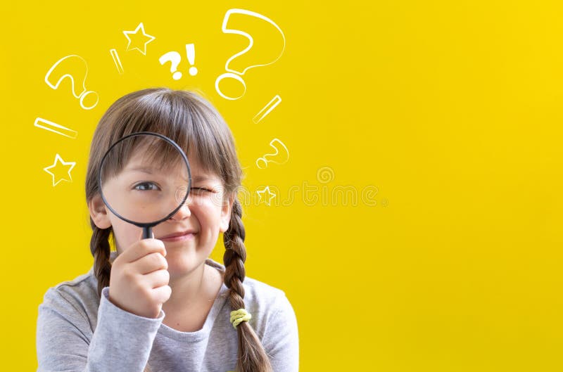 Cute suspicious little girl looking through a magnifying glass on yellow background with copy space royalty free stock photography