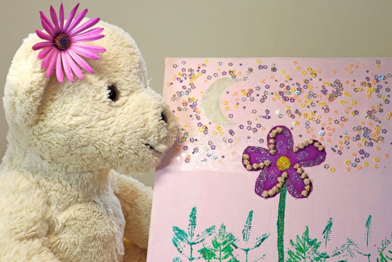 Teddy bear with a purple flower looking at a painting