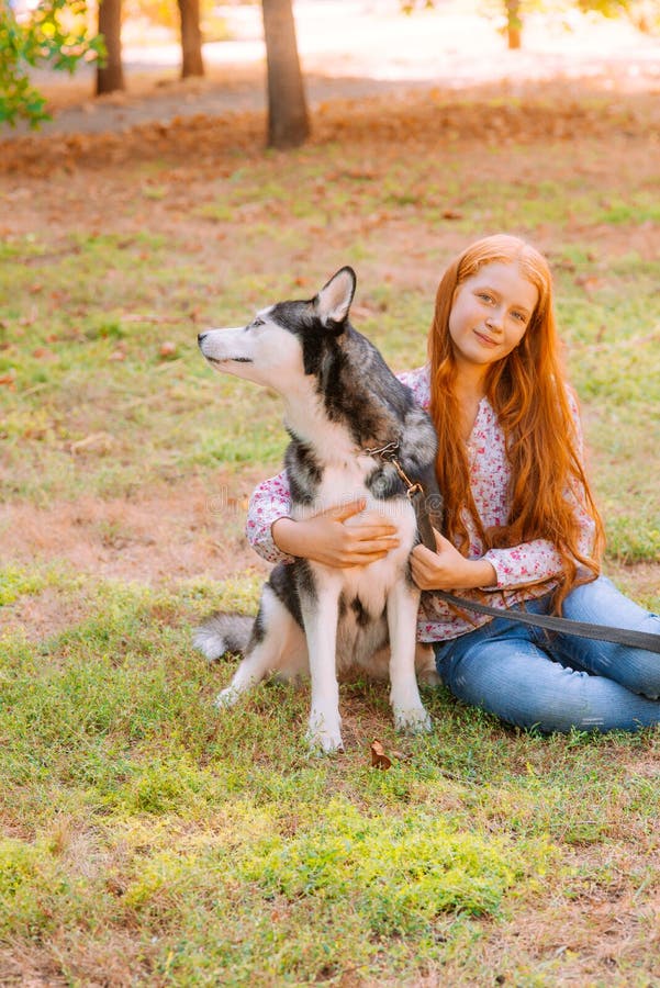 Cute Teen Girl With Red Long Hair Walks With Her Husky Breed