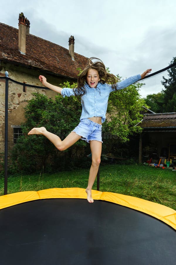 Cute teenage girl jumping on trampoline royalty free stock photography.