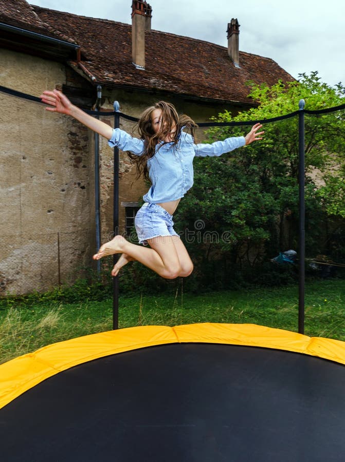 Cute teenage girl jumping on trampoline.