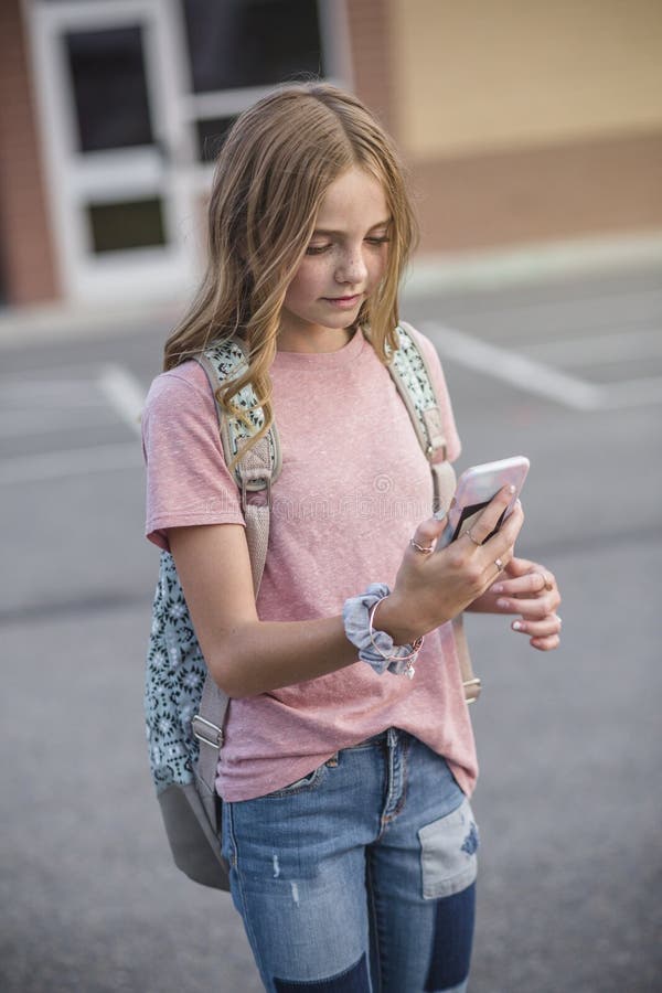 Teenage Girl walking to school and using her cell phone