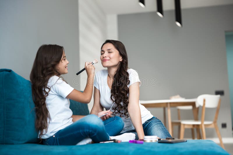 Cute teenager daughter applying loose powder to her young beautiful mother`s face with makeup brush royalty free stock photos Cute teenager daughter applying loose powder to her young beautiful mother`s face with makeup brush royalty free stock photos