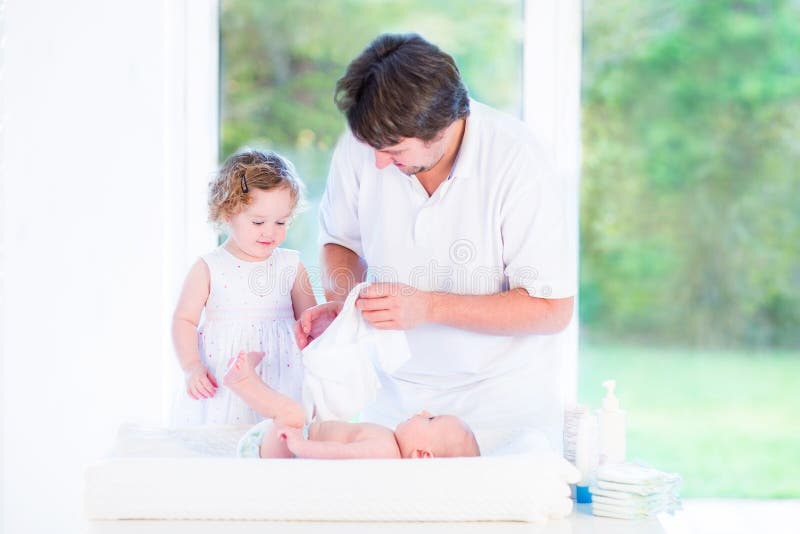 Cute toddler girl helping her father to change diaper royalty free stock photos Cute toddler girl helping her father to change diaper royalty free stock photos