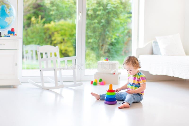 Cute toddler girl playing in a white room with big