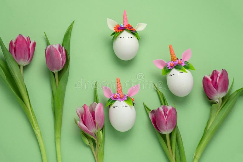 Unicorn eggs and pink tulips on a green background , cute minimal easter card stock photography