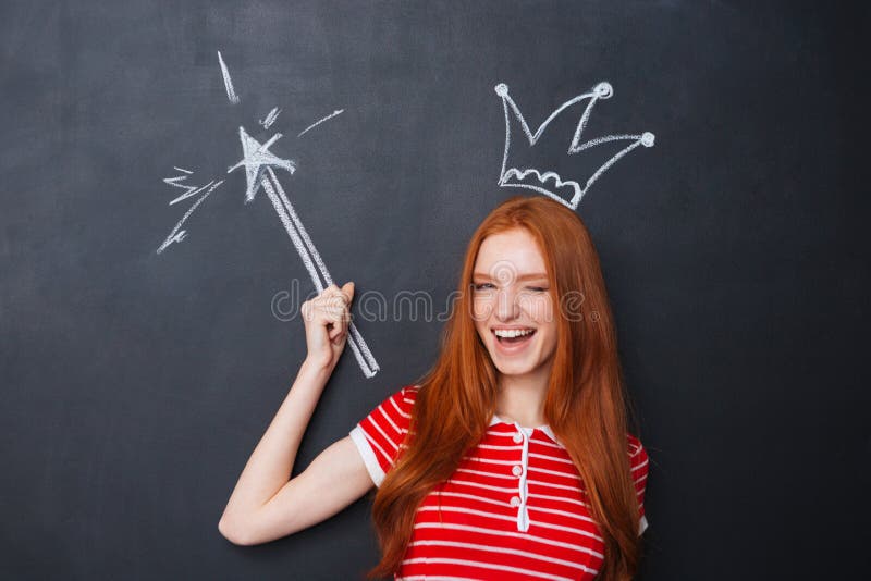 Cute woman winking with crown and magic wand over chalkboard royalty free stock photo Cute woman winking with crown and magic wand over chalkboard royalty free stock photo