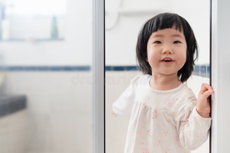 Cute 2 year old Asian toddler girl feeling exciting pointing behind and shows her mom the shower room, enjoy taking a bath, mother