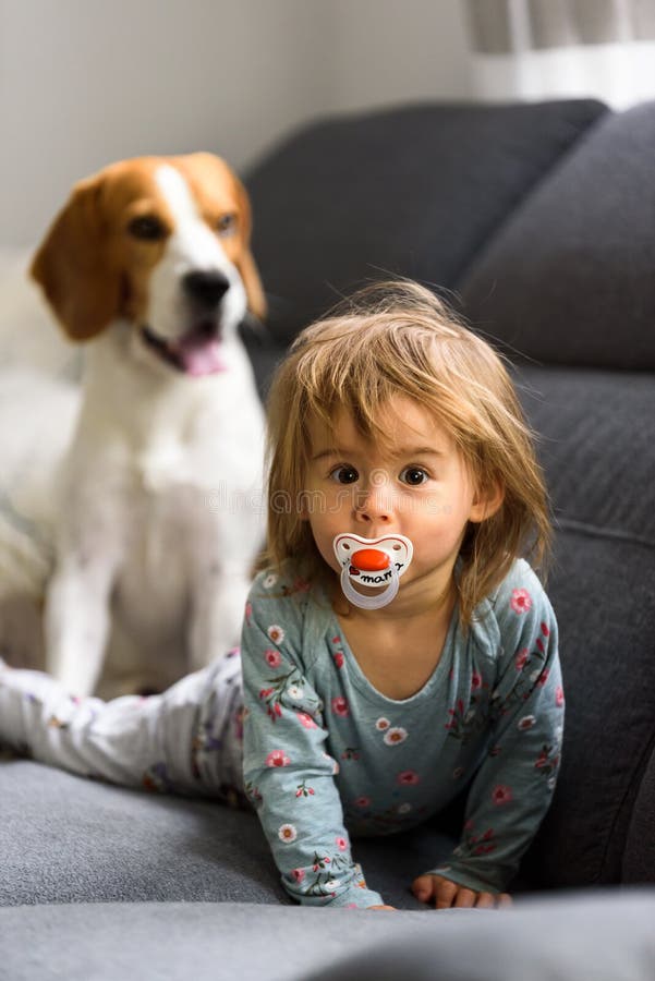 Cute 2 year old Baby girl on a bed on her belly with head up looking into camera with her big eyes.