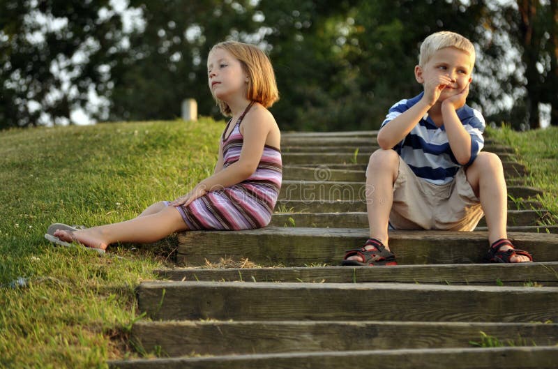 Cute young boy and girl sitting on steps of park