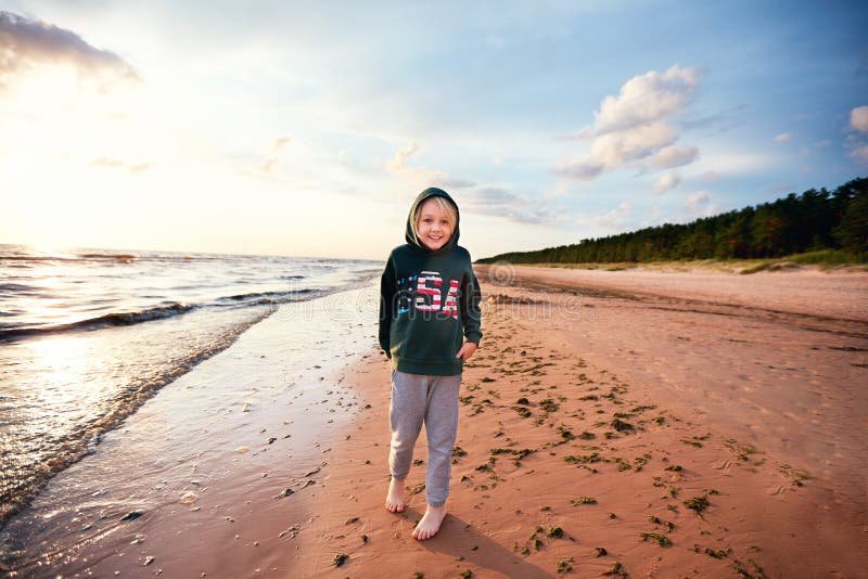 Cute young boy having fun on the sandy beach near the pine tree forest, candid lifestyle royalty free stock photo Cute young boy having fun on the sandy beach near the pine tree forest, candid lifestyle royalty free stock photo