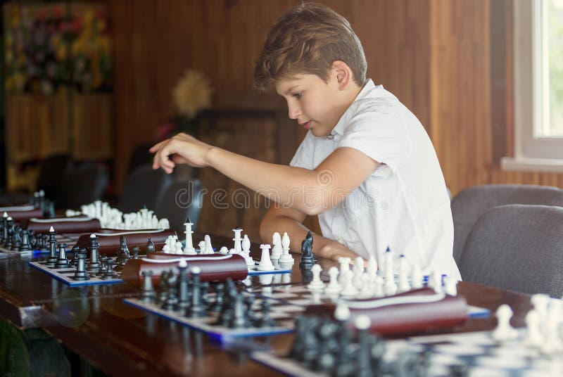Cute, young boy plays chess with wooden chessboard. Chess tournament, lesson, camp, training stock photography Cute, young boy plays chess with wooden chessboard. Chess tournament, lesson, camp, training stock photography