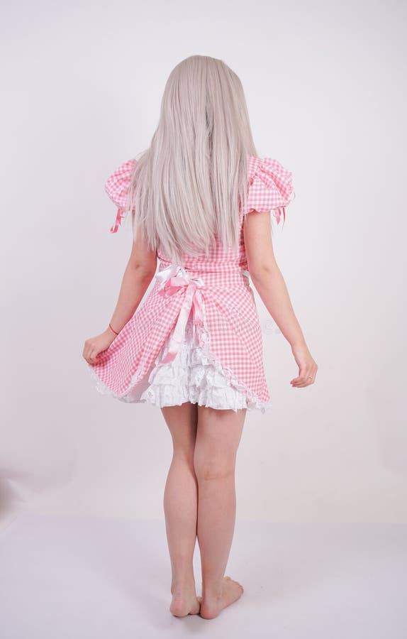 Cute young caucasian teen girl in pink plaid Bavarian dress with apron posing on white Studio solid background royalty free stock photo Cute young caucasian teen girl in pink plaid Bavarian dress with apron posing on white Studio solid background royalty free stock photo