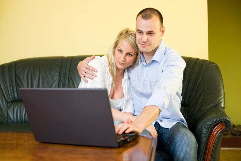 Cute young couple with laptop at home. stock photo