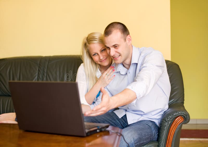Cute young couple using net thru laptop. stock photos