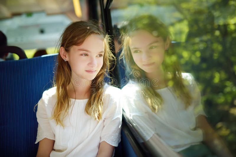 Cute young girl traveling by train on summer day. Child sitting by the window of railway wagon and looking outside