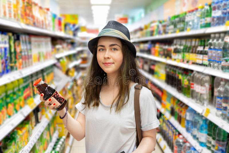 Cute young woman chooses a bottle of juice in the supermarket. Tint stock images Cute young woman chooses a bottle of juice in the supermarket. Tint stock images