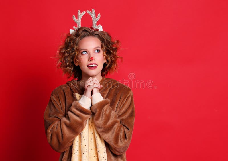 Carino ridicolo giovane donna renne di natale aspetto su un fa desiderio sul colorato.