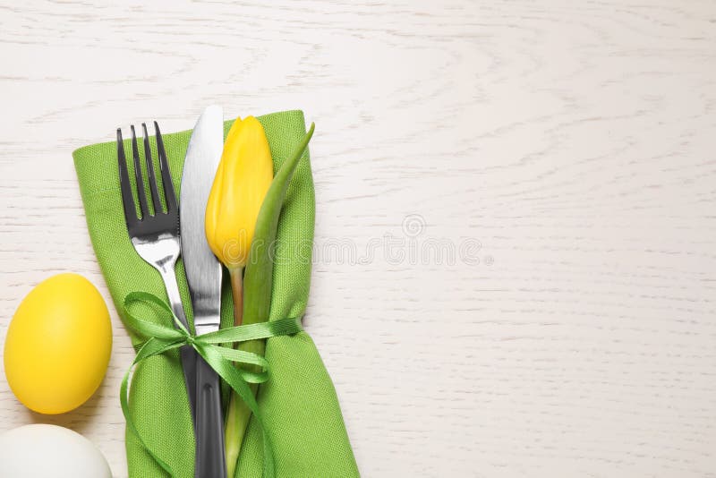 Cutlery set and eggs on white wooden table, flat lay with space for text. Easter celebration
