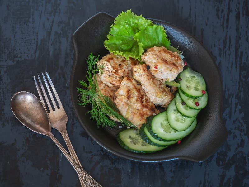 Cutlets διατροφής της Τουρκίας Fark με τα κολοκύθια σε ένα μαύρο πιάτο με τα λαχανικά με τις φέτες αγγουριών και το φρέσκο μαρούλ στοκ φωτογραφίες με δικαίωμα ελεύθερης χρήσης Cutlets διατροφής της Τουρκίας Fark με τα κολοκύθια σε ένα μαύρο πιάτο με τα λαχανικά με τις φέτες αγγουριών και το φρέσκο μαρούλ στοκ φωτογραφίες με δικαίωμα ελεύθερης χρήσης