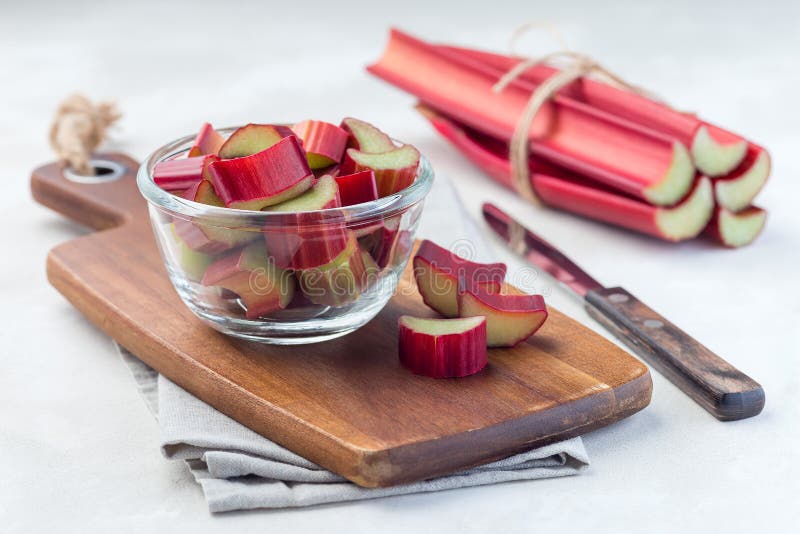 Cutted rhubarb in a glass dish and on  wooden board, horizontal