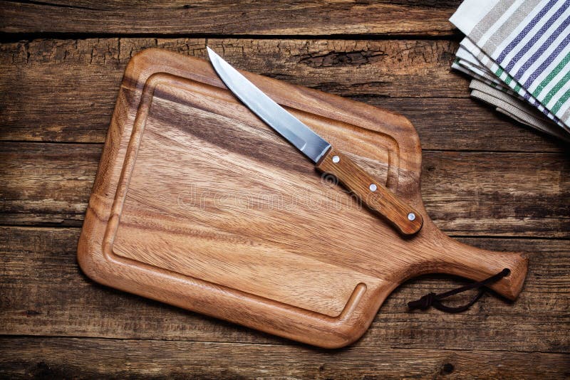 Tagliere e un coltello da cucina sul vecchio sfondo di legno.