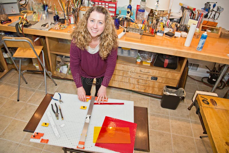 Blondínka pomocou glass cutter na rezané pásy umeleckého skla pre umelecké projekty.