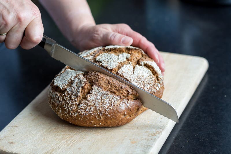 Cutting loaf of bread with knife on cutting board