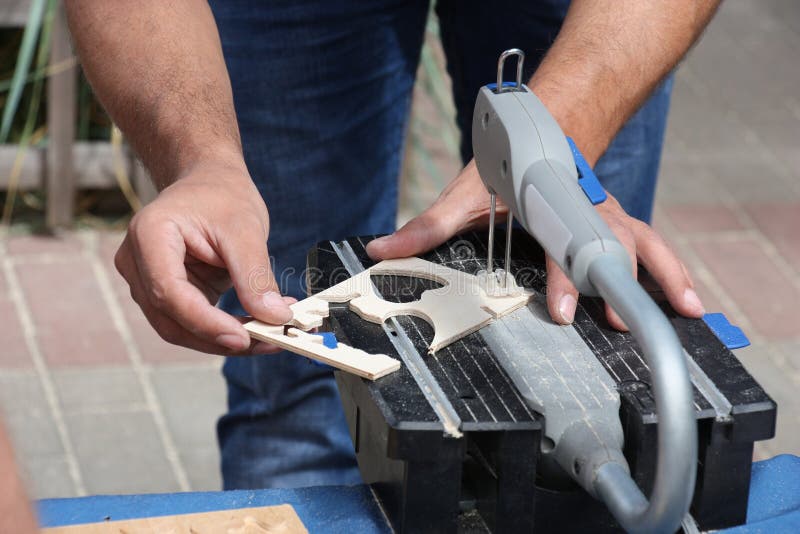Download Man Cuts A Plywood Plate Using A Green Electric Circular Saw Tool With Yellow Chips On A Work ...