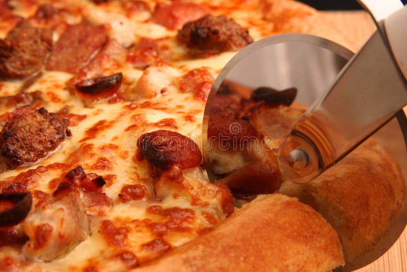 A hot, fresh pizza being cut close up. A hot, fresh pizza being cut close up