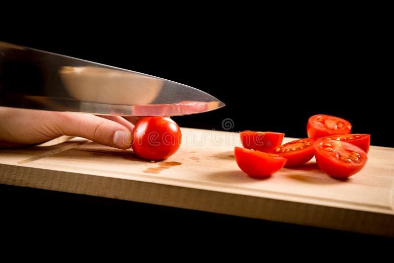 Cutting red cherry tomatoes on wooden board stock photo Cutting red cherry tomatoes on wooden board stock photo