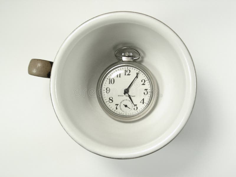 A coffee cup holds a pocket watch showing a time of five minutes past five o'clock. A coffee cup holds a pocket watch showing a time of five minutes past five o'clock.
