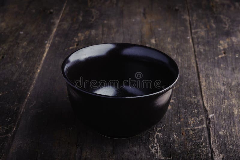 Cuvette noire vide de porcelaine sur le fond en bois grunge images stock Cuvette noire vide de porcelaine sur le fond en bois grunge images stock