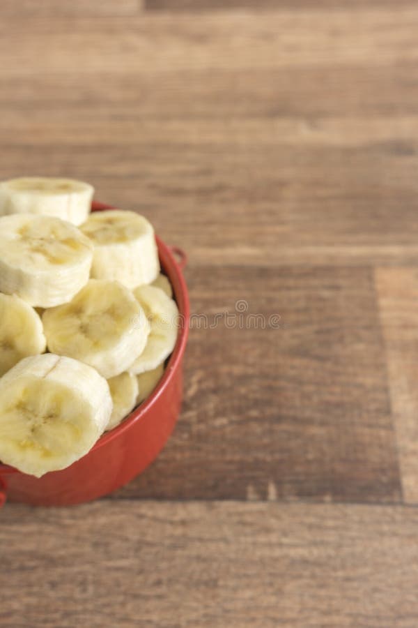 Cuvette rouge avec des tranches de banane sur le fond en bois image libre de droits Cuvette rouge avec des tranches de banane sur le fond en bois image libre de droits