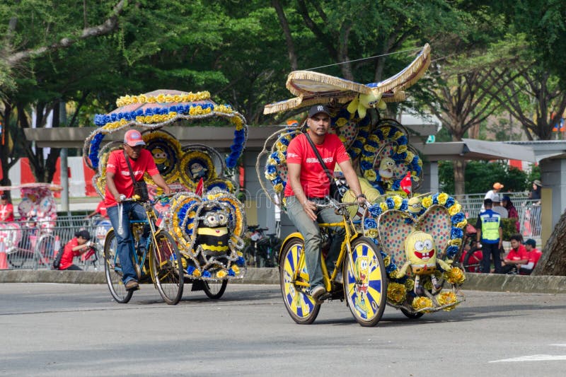 Cyberjaya, Malaysia, 2018-03-31: Tourist entertainment - trishaw on his customized tricycle transport, brightly decorated with children`s cartoon and flowers. Public attraction.