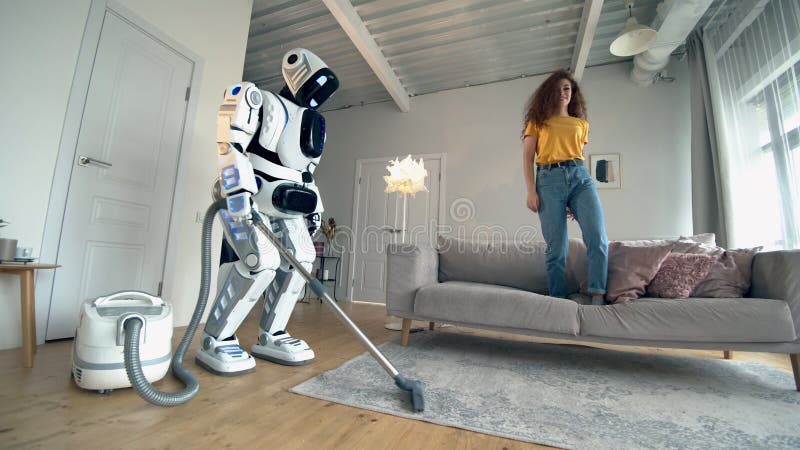 Mujer relajándose en el sofá mientras robot aspirador haciendo quehaceres  domésticos