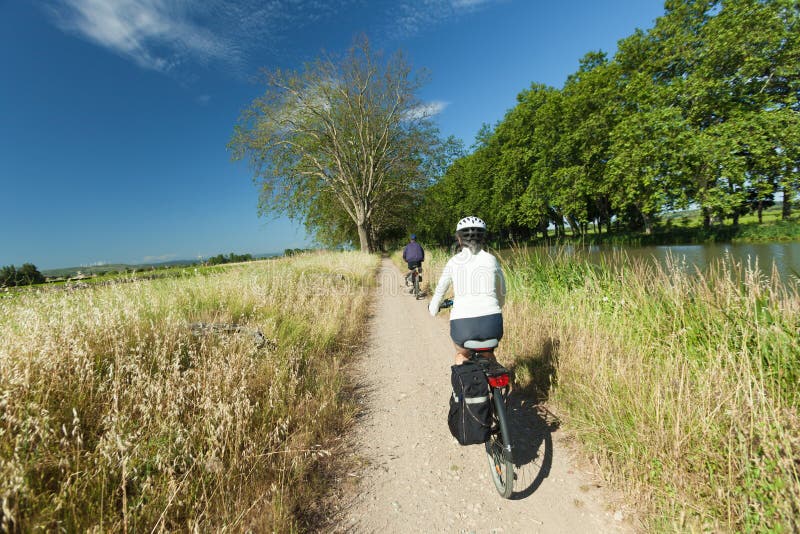 Una mujer a hombres montando una bici sobre el El camino más cercano un rio sobre el en Francia.