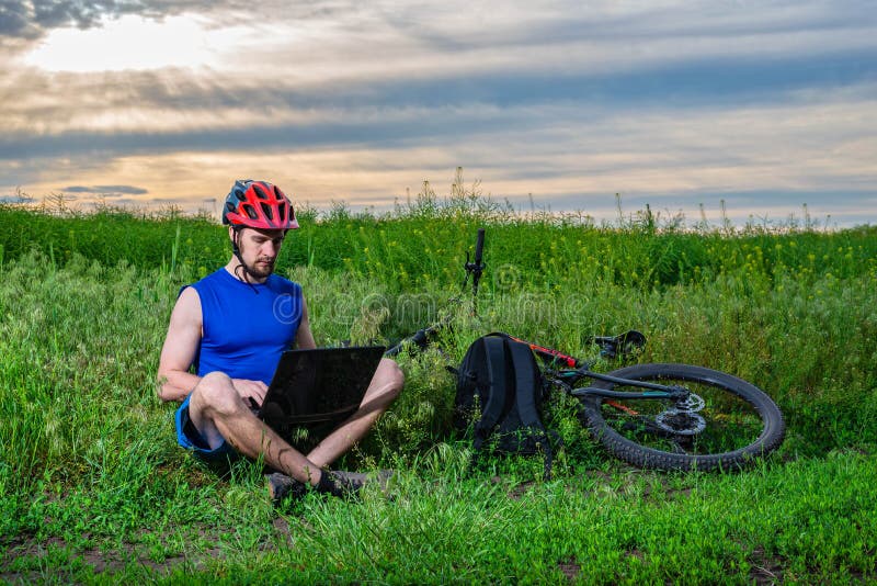 Cyclist Working on a Laptop while Cycling. Remote Work Outdoors Stock