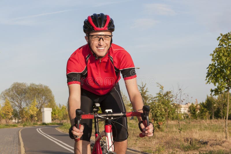 Cycliste caucasien de sourire de route pendant le tour sur le vélo dehors photos libres de droits Cycliste caucasien de sourire de route pendant le tour sur le vélo dehors photos libres de droits