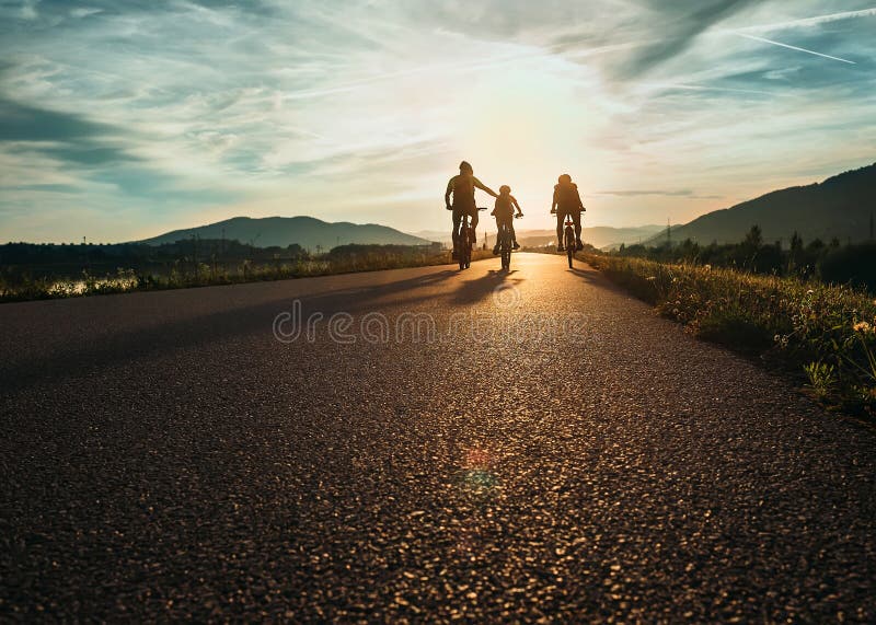 Cyclists family traveling on the road at sunset